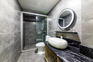 A modern bathroom with a glass-enclosed shower, a white toilet, and a marble sink with a round mirror. - Shaoxing Shun'an Collection Hotel (Lu Xun's Hometown Yintai Branch) (Shaoxing)