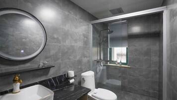A modern bathroom with a marble sink, toilet, and a glass-enclosed shower.