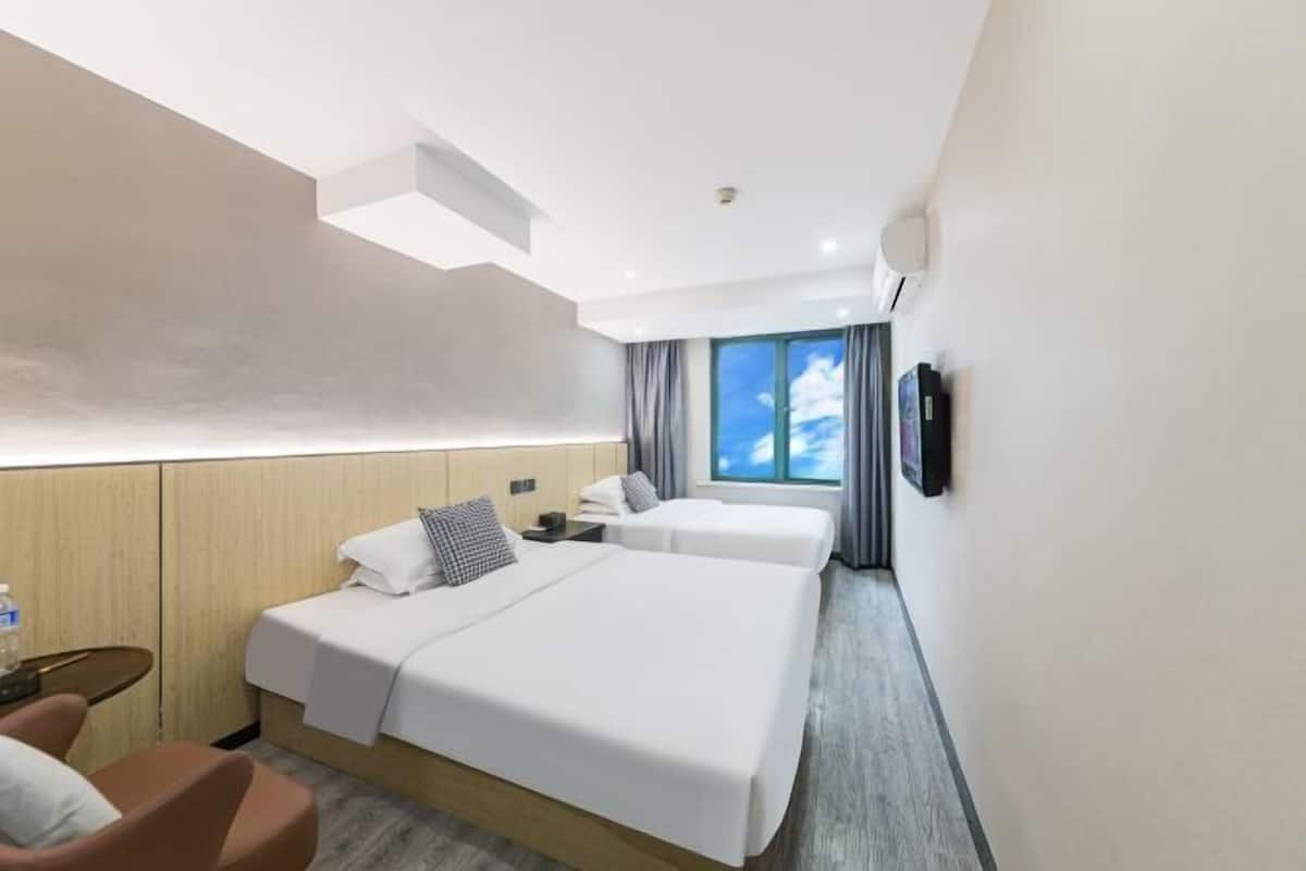 Una habitación de hotel con dos camas, un escritorio, una silla, un televisor y una ventana con cortinas.