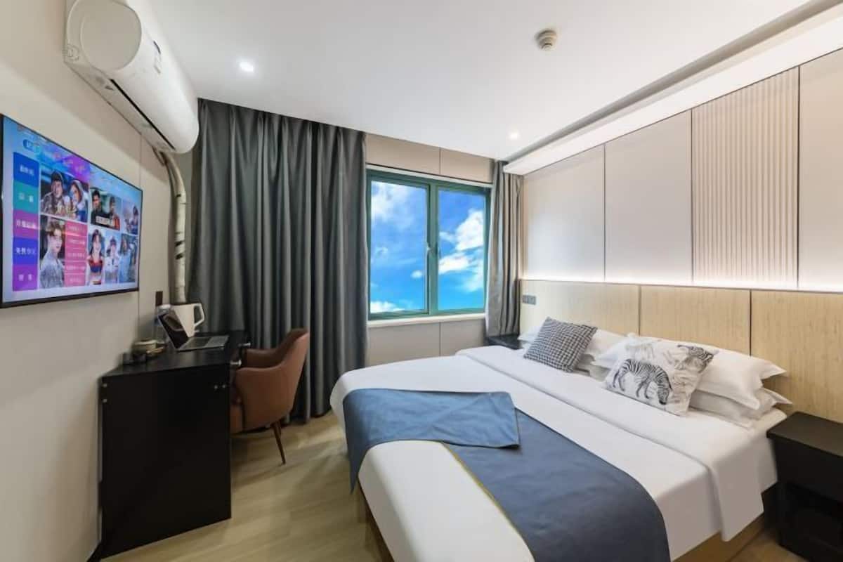 Una habitación de hotel moderna con una cama grande, un escritorio, una silla y una ventana con vistas.