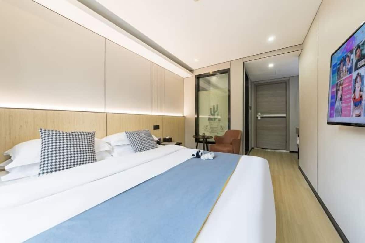 Una habitación de hotel moderna con una cama grande, un escritorio, una silla y un televisor.