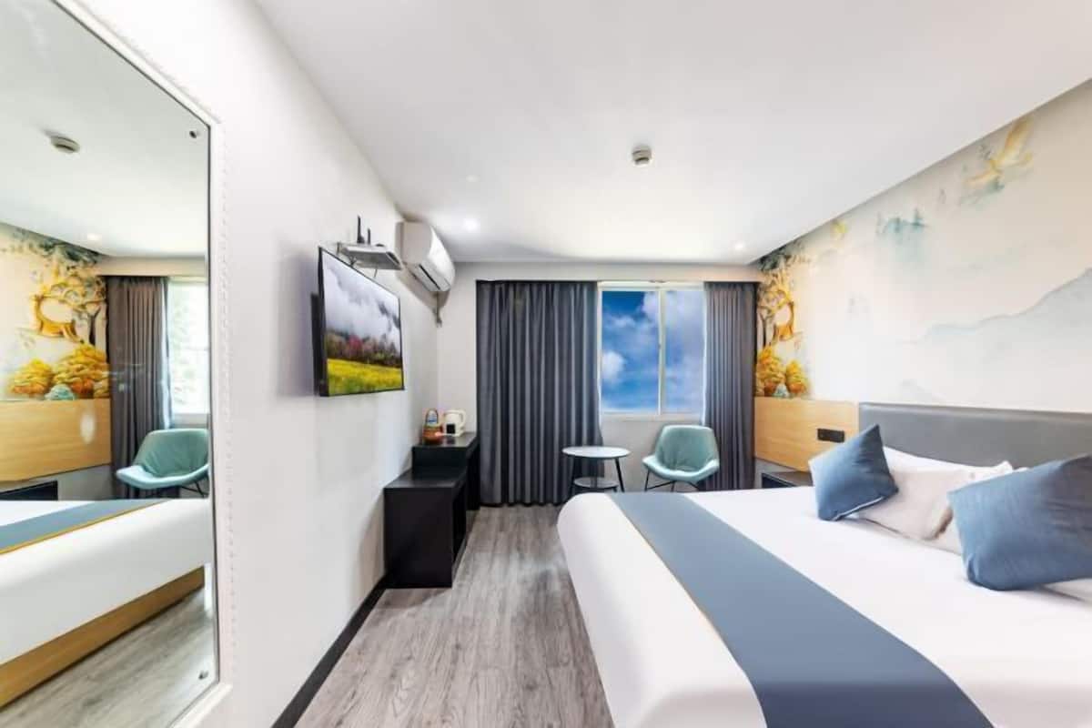 Una habitación de hotel con una cama grande, un escritorio, una silla, una mesita y un espejo amplio.