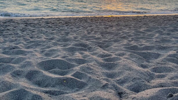 Ein Strand mit einem Sonnenuntergang im Hintergrund.