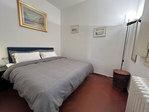 A bedroom with a bed, a nightstand, a lamp, and a radiator. - GP Old Bridge View (Firenze)