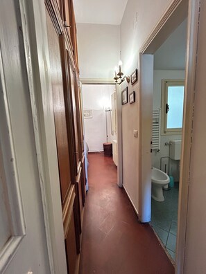 A narrow hallway with wooden paneling on one side and a bathroom visible through an open door. - GP Old Bridge View (Firenze)