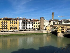 A river with a stone bridge and buildings along the riverbank. - GP Old Bridge View (Firenze)