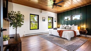 A bedroom with a wooden ceiling, a bed with white bedding, and a view of trees through the windows. - Epic mountain views, Hot tub and Game room (Bethel)