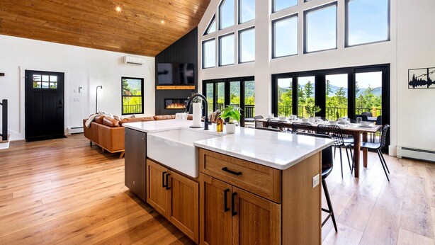 A spacious kitchen with a large island, wooden cabinets, and a view of the outdoors through large windows. - Epic mountain views, Hot tub and Game room (Bethel)