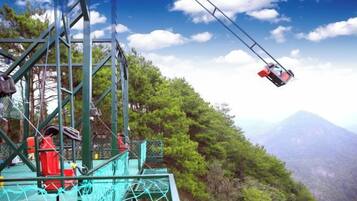 A cable car system with a cable car in mid-air, a metal structure, and a mountainous landscape.