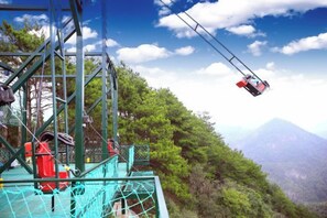 Sistema de teleférico con un cable car en el aire, una estructura metálica y un paisaje montañoso.