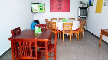 A dining area with a round table, wooden chairs, and a television mounted on the wall.