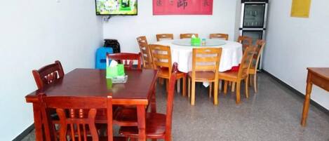 Un comedor con una mesa redonda, sillas de madera y un televisor montado en la pared.