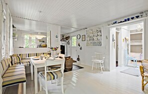 A bright, white interior with a dining area, a sofa, and a kitchen visible.