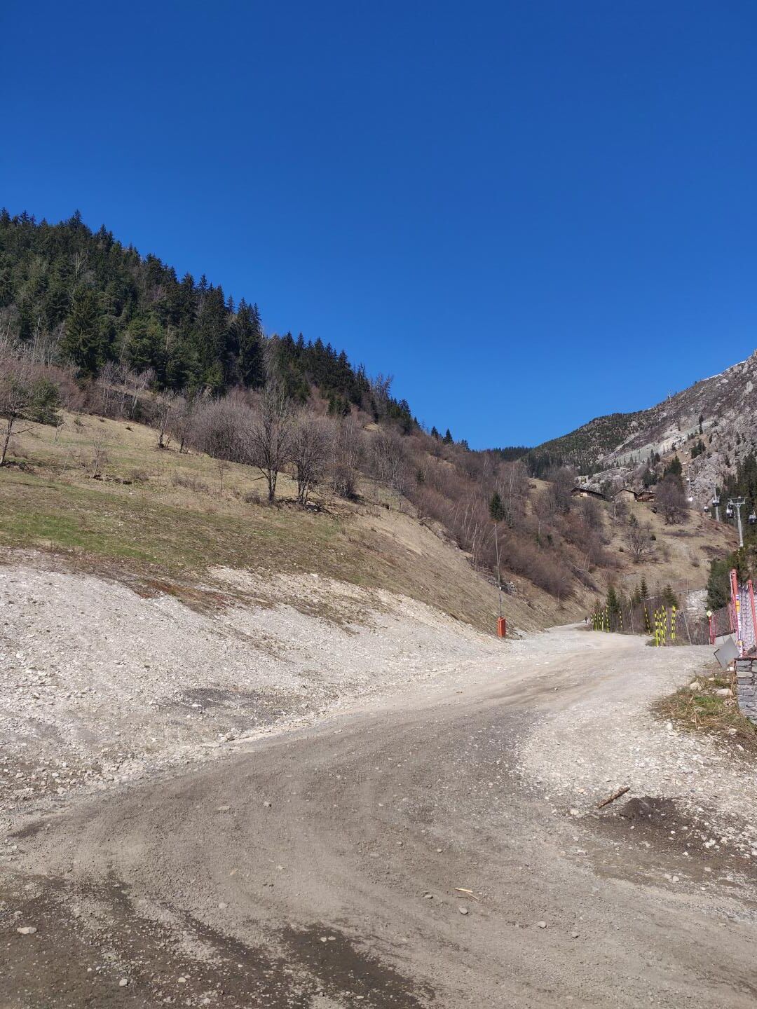 Un camino rural con un sendero de tierra que lleva a una montaña.
