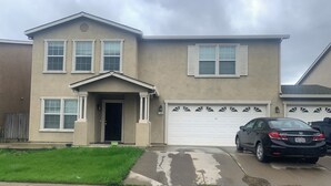 Une maison d’habitation avec un garage, une allée et une voiture garée.