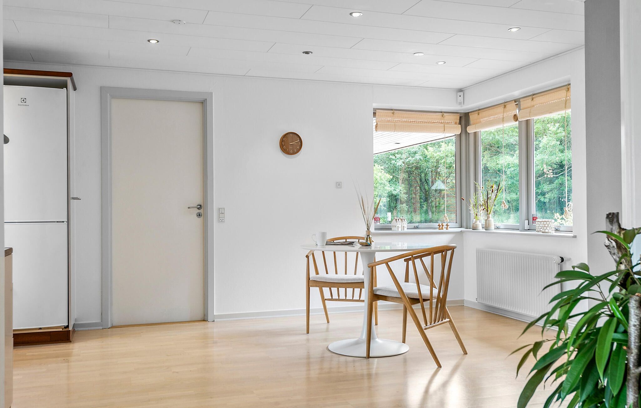 Une cuisine moderne avec un réfrigérateur blanc, des chaises en bois et une table à manger.