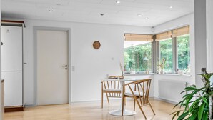 A modern kitchen with a white refrigerator, wooden chairs, and a dining table. - Lovely home in Grindsted with lake view (Grindsted)
