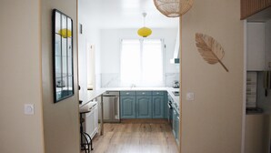 A kitchen with teal cabinets, a white countertop, and a large window.