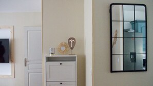 A room with a white cabinet, a mirror with a grid pattern, and a door.