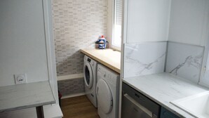 A laundry room with a washing machine, dryer, and a countertop with a bottle of detergent.