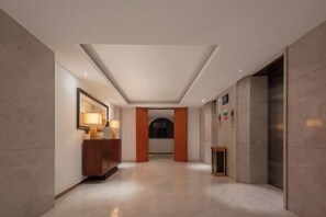 A hotel lobby with a reception desk, a framed picture, and a door leading to an elevator. - Qianshan Heyue Hotel (Guiyang)