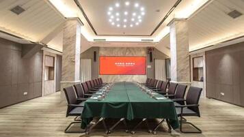 Sala de conferência com uma mesa comprida, cadeiras e tela de projeção.