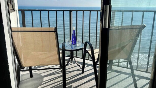 A balcony with a table, two chairs, and a bottle of water.