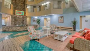 A lobby with a stone fireplace, multiple balconies, and a pool area with lounge furniture.