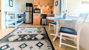 A compact kitchen with a refrigerator, microwave, and wooden cabinets. There's a dining table with chairs and a rug. - Stunning mountain views, quiet, peaceful, unique, private attached guest suite (Bend)