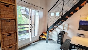A spacious room with a wooden staircase, a dining table, and wicker baskets. - Spacious, modern 4-room duplex apartment, comfortable, quiet, ski in, ski out (Risoul 1850)