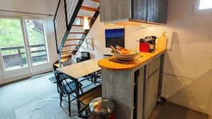 A modern kitchen with a wooden ceiling, a dining area with a table and chairs, and a staircase leading to an upper level. - Spacious, modern 4-room duplex apartment, comfortable, quiet, ski in, ski out (Risoul 1850)