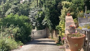 A gravel path leading to a wooden gate surrounded by lush greenery and potted plants. - VILLA HORTUS MARIAE - LE THORONET (LE THORONET)