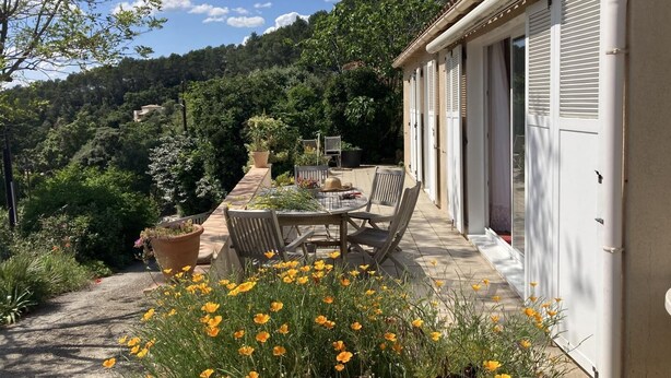 A patio with a table and chairs, surrounded by potted plants and yellow flowers. - VILLA HORTUS MARIAE - LE THORONET (LE THORONET)