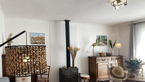 A cozy living room with a sofa, a wooden coffee table, a fireplace, and a dining area with a table and chairs. - VILLA HORTUS MARIAE - LE THORONET (LE THORONET)
