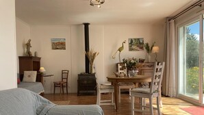 A cozy living room with a sofa, a fireplace, a dining table, and a large window. - VILLA HORTUS MARIAE - LE THORONET (LE THORONET)