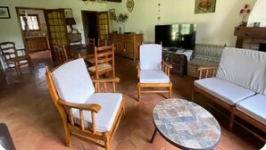 Una sala de estar con muebles de madera, un televisor y un piso con estampado.