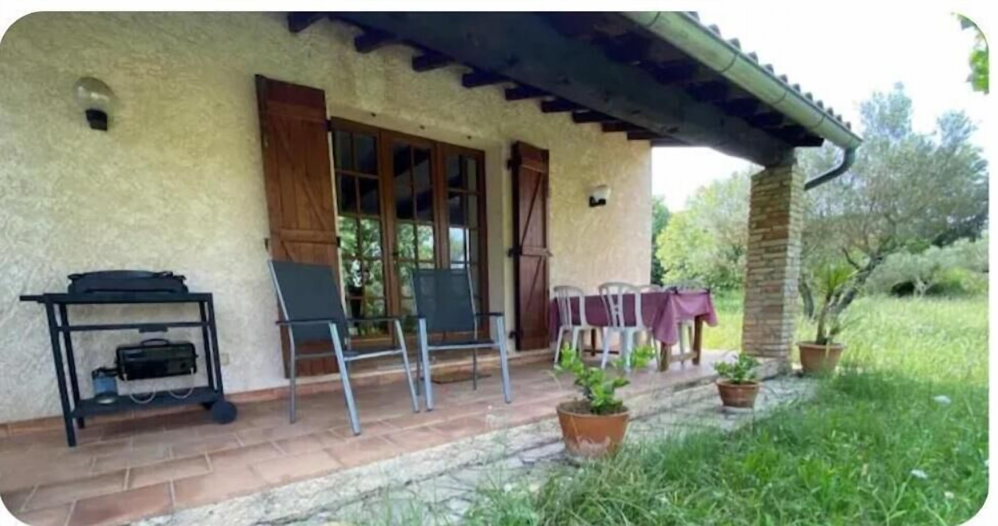 A rustic building with a covered porch, outdoor seating, and potted plants.
