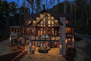 Une grande cabane en bois avec une vaste terrasse, plusieurs niveaux et une façade en pierre.