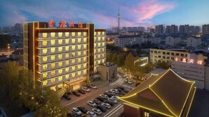 A multi-story hotel with a modern design, featuring a prominent entrance and a parking lot.