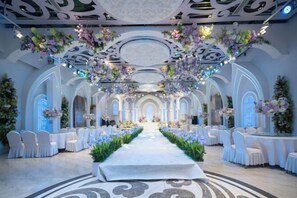Un espace intérieur doté d’une allée centrale, de chaises blanches et de décorations florales.