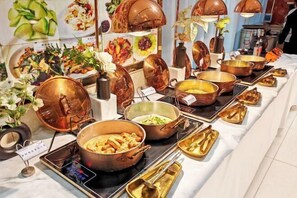 A buffet setup with various dishes and utensils. - Jinxin Hostel (Laoling)