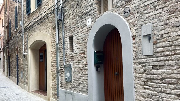 Un bâtiment en pierre doté de deux portes cintrées, chacune étant surmontée d’une porte en bois et agrémentée d’une petite boîte aux lettres fixée au mur.
