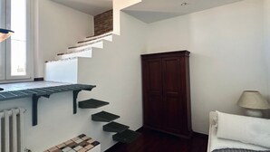 Une pièce avec un escalier, un radiateur, une armoire et un lit.