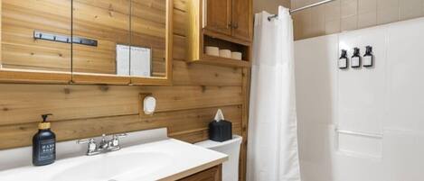 Un baño con paneles de madera, un lavabo blanco, un inodoro y una cortina de ducha.