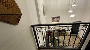 Un escalier avec une rampe en fer forgé noir, un mur blanc et un tableau encadré accroché au mur.