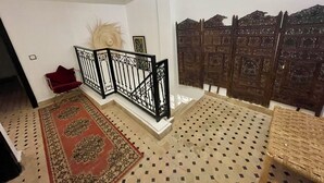 Un escalier avec un revêtement de sol à motifs, une chaise rouge et un panneau décoratif mural.