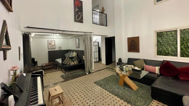 Un vaste salon comprenant un piano, un canapé, une table basse et un escalier menant à un niveau supérieur.