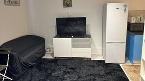A compact room with a bed, a TV on a stand, a refrigerator, and a microwave on a blue counter. - 1 bedroom studio central london 220 (London)