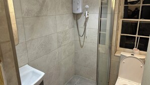 A small, tiled bathroom with a glass shower enclosure, a toilet, and a sink. - 1 bedroom studio central london 220 (London)