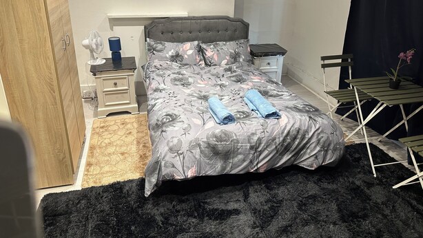 A neatly arranged bedroom with a bed, bedside tables, a chair, and a small table with a plant. - 1 bedroom studio central london 220 (London)